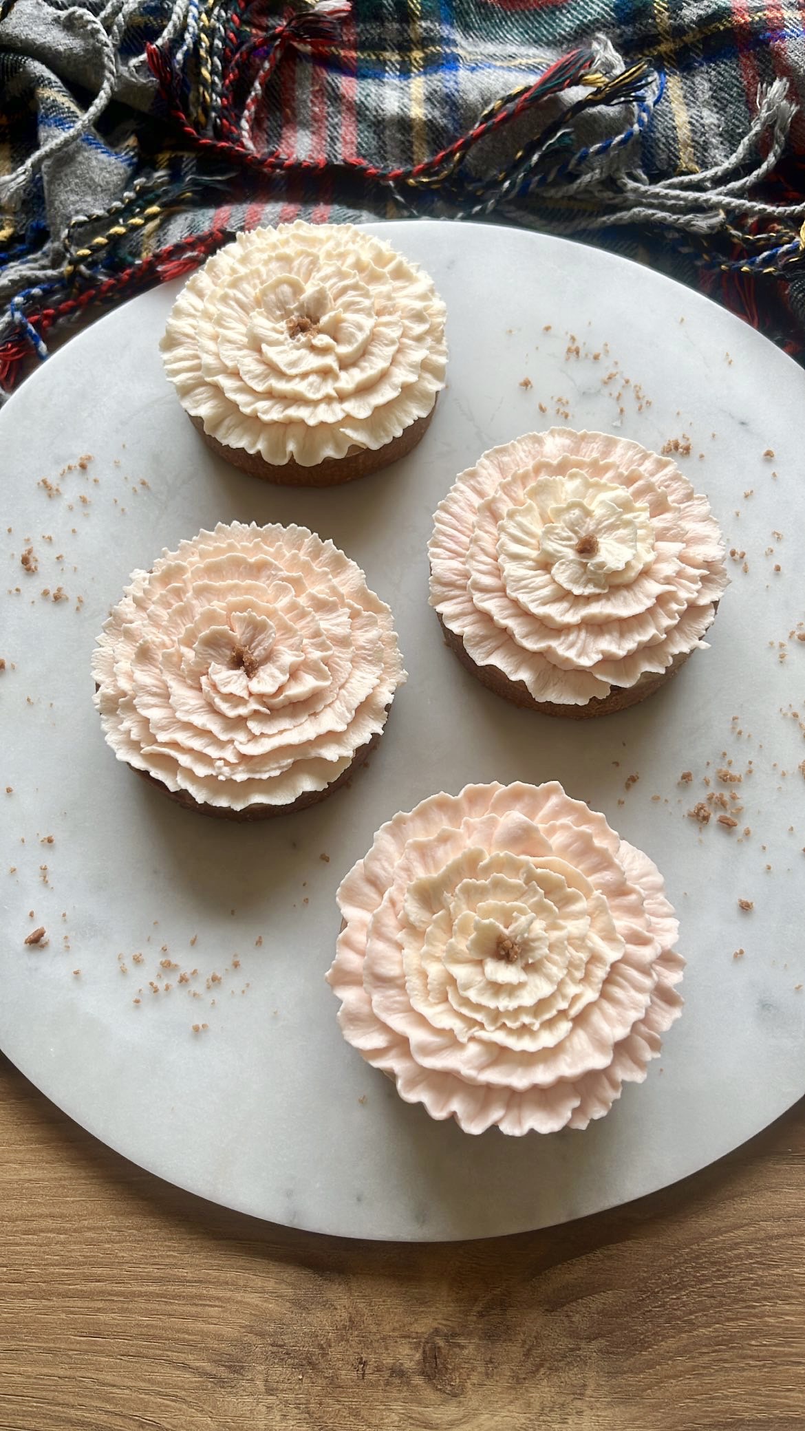 Four tarts decorated with pink flower-shaped cream piping on top